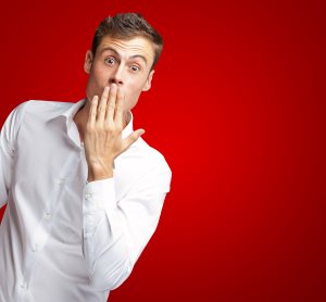 Man Covering His Mouth With Hand On Red Background