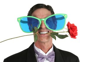 man in a tuxedo with a rose in his mouth and oversized sunglasses