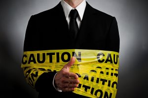 man wearing a suit with caution tape extending his hand to shake