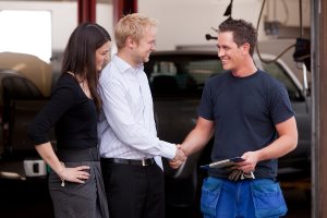 mechanic shaking hands with a customer couple