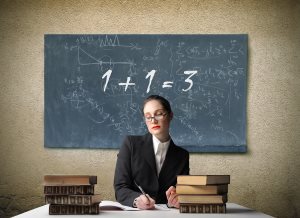 chool teacher sitting at a desk with wrong addition on blackboard