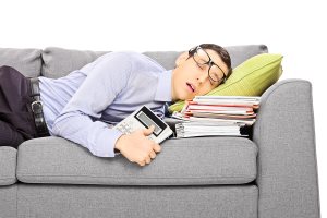Exhausted young businessman sleeping on a couch with many documents
