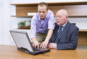 company director being shown how to operate a laptop by a computer technician