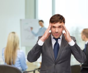 stressed buisnessman or teacher having headache at office