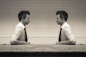 two men are mirroring each other at a desk