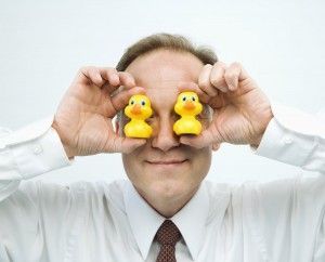 businessman holding rubber ducks up to face