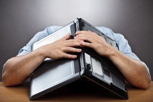 exhausted businessman covering his head with his laptop