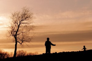 Silhouette of a parent opening his arms to a child running toward him