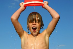 Boy dumping a bucket of water on his head