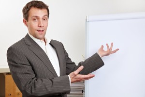 Business man during presentation pointing to white flipchart