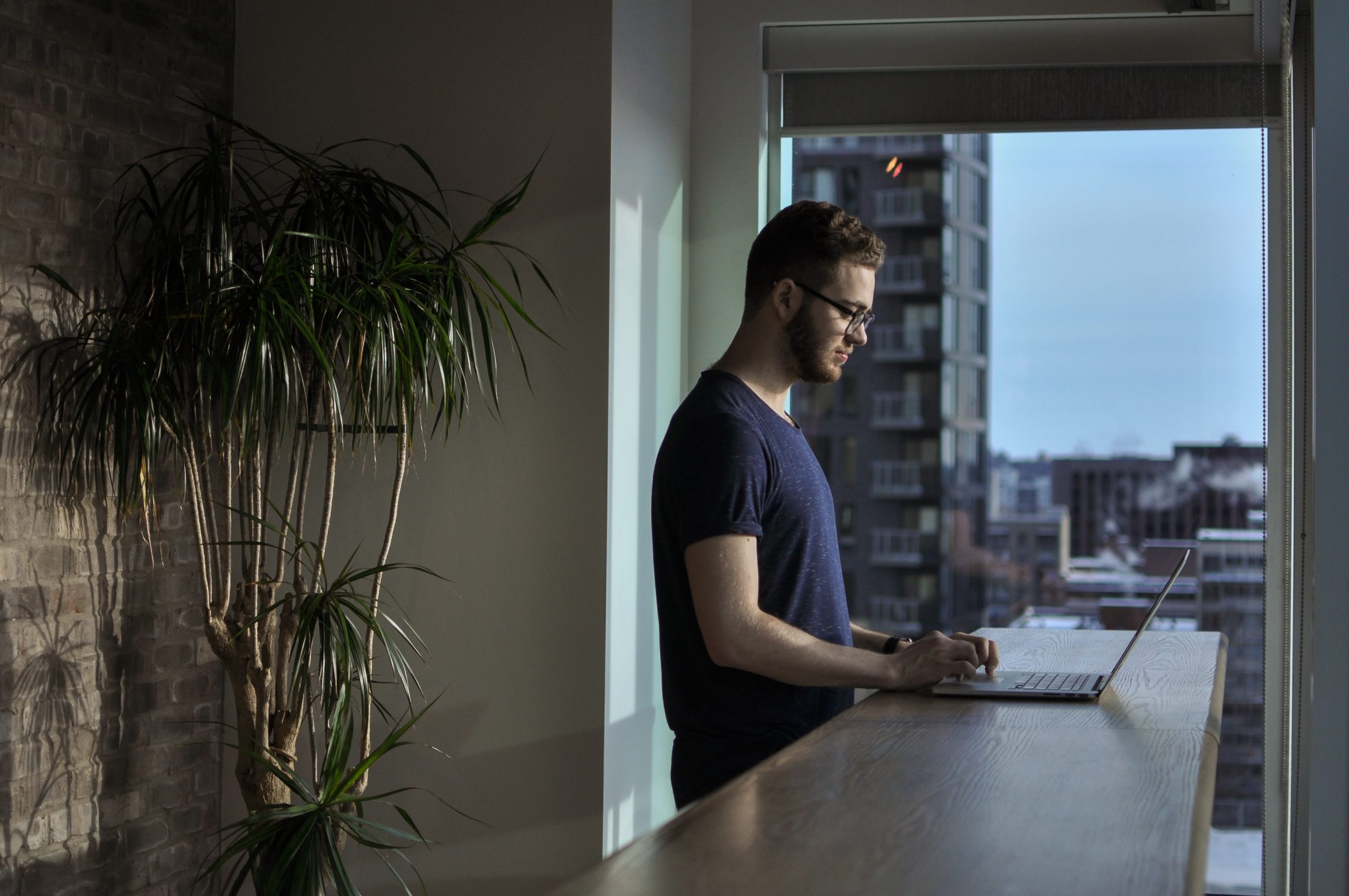 Man standing at his kitchen counter, working on laptop